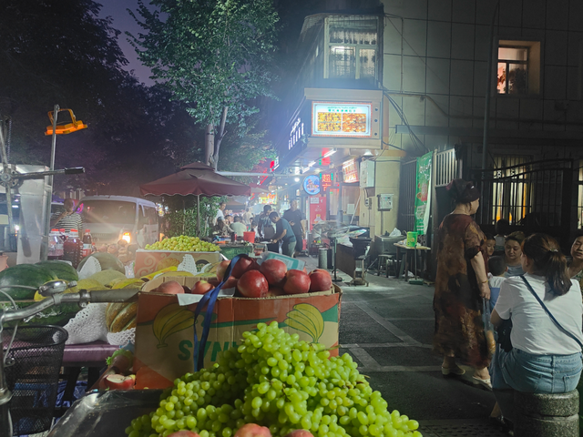 乌鲁木齐和田二街上食客众多，路旁摆满了瓜果摊、烧烤摊。 高宇婷 图