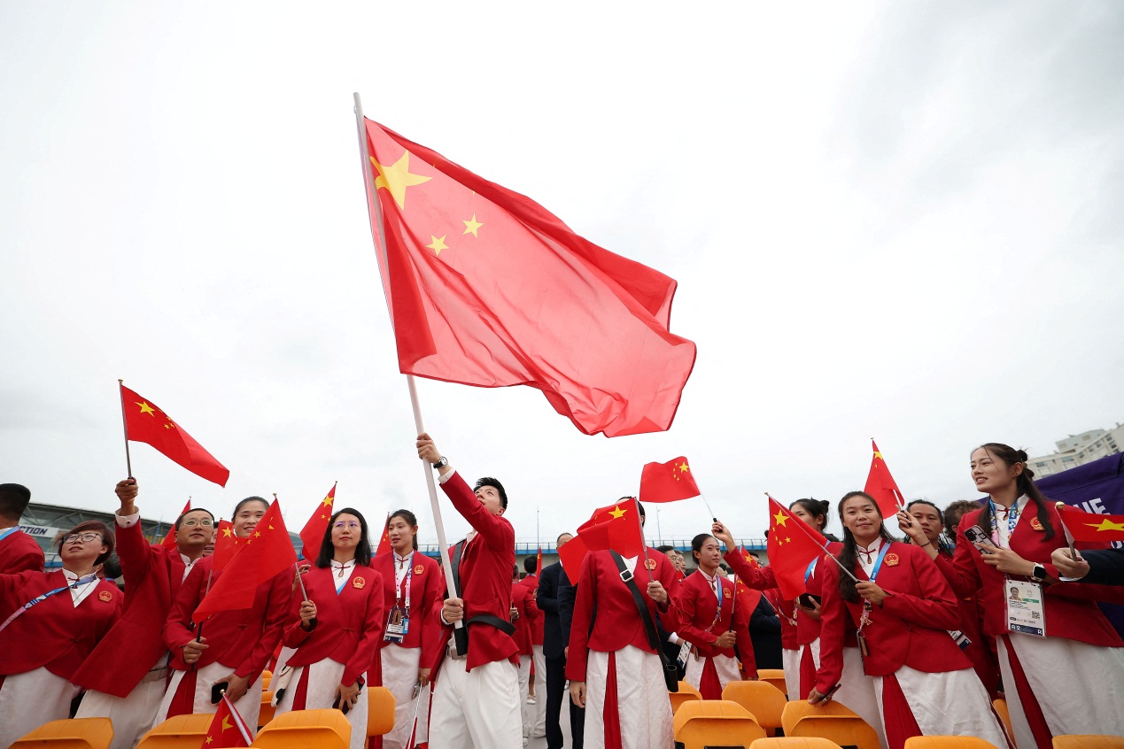 中国体育代表团运动员手举国旗,乘坐