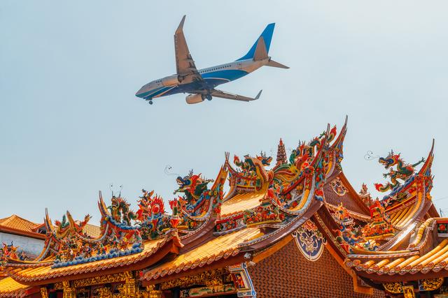 厦门航空一架客机从厦门市清水宫寺庙上空飞过，厦门正在建设全新的国际机场。 视觉中国 图