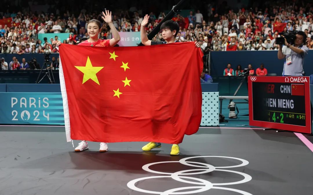 陈梦(左)和孙颖莎拿着国旗向球迷致意.图/新华社