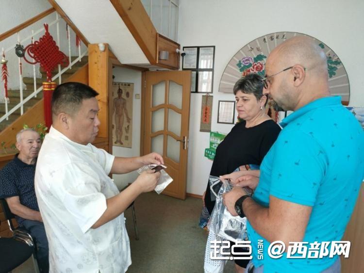 李洛西（左一）向国际友人介绍中药产品功效。