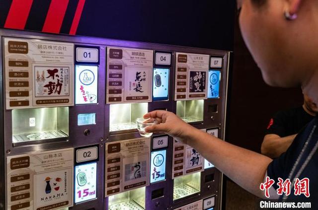 图为一位品鉴者体验参展商带来的可扫码注册后自助品酒的机器。中新网记者 侯宇 摄