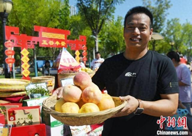 在德州市庆云县的大集上，摊主展示自家桃园收获的桃子。(资料图)庆云县委宣传部供图