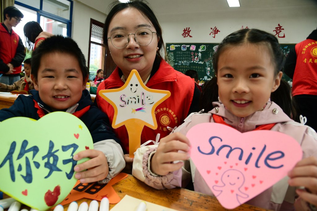 2024年11月20日，江苏镇江，在江苏省镇江市朱方路小学，江苏科技大学志愿者和小学生在展示绘制的问候卡。