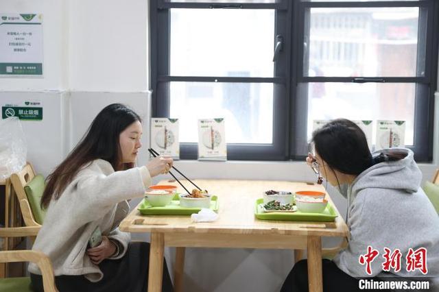 11月21日，江西南昌东湖区，中午饭点时间，两位年轻人在光明社区幸福食堂内用餐。中新社记者 刘力鑫 摄