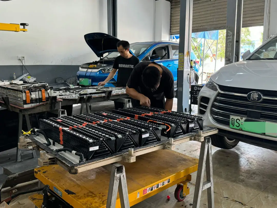 （余松门店的汽修工在维修电池，《21汽车·一见Auto》/摄）