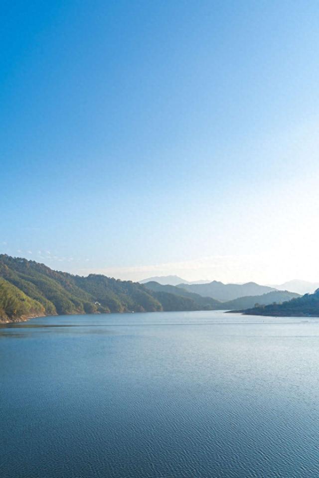 安徽省六安市霍山县佛子岭水库,在蓝天下,水面平静如镜,远处山峦起伏