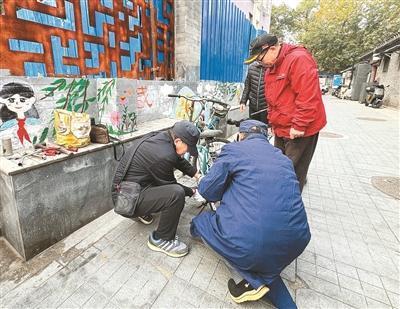 “帮把手公益服务队”的于师傅（左二）为居民修理自行车。记者 霍旻含 摄