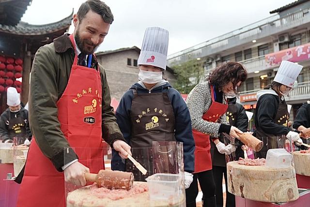 法国教师詹子重（左）在两岸小吃技艺千人体验活动中体验用木槌捶打肉馅。 澎湃新闻记者 王珏玮 图