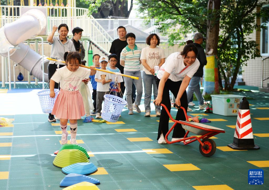 资料图:幼儿园的小朋友和家长一起参加亲子趣味游戏.图/新华社