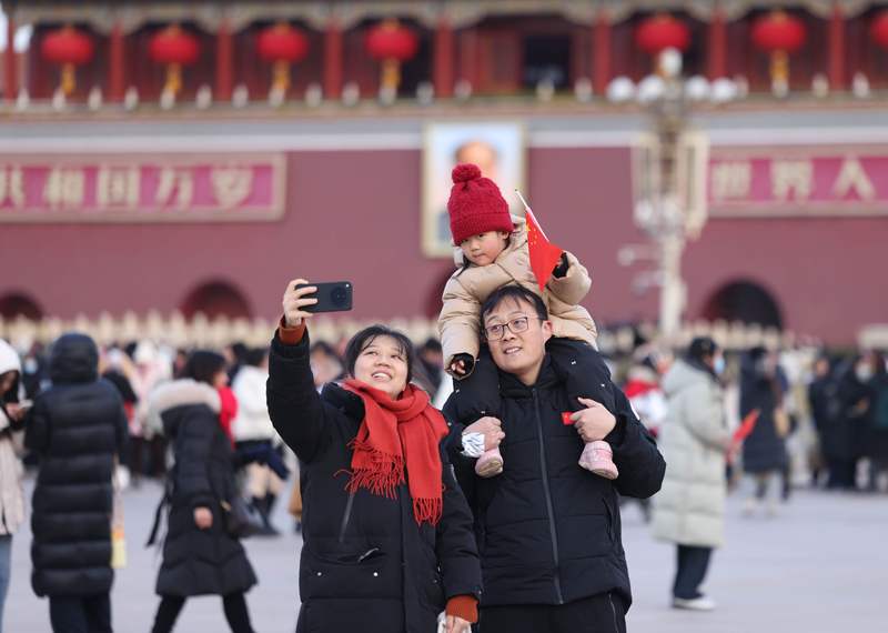 小一又友手持国旗和爸爸姆妈自拍。新京报记者 李木易 摄