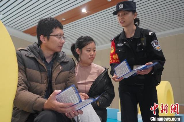 图为民警黄欣向民众发放反诈宣传手册。陈大鹏 摄