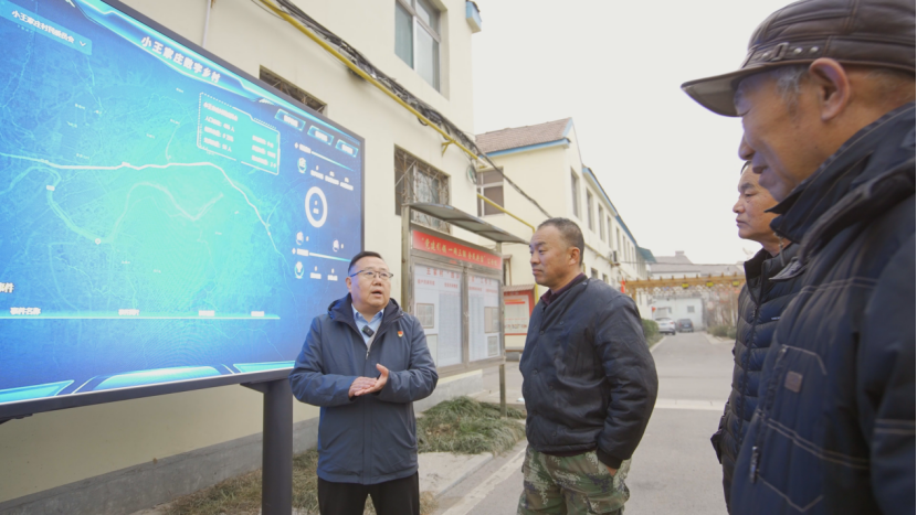 图为牛继林为村民讲解智慧大屏的功用。