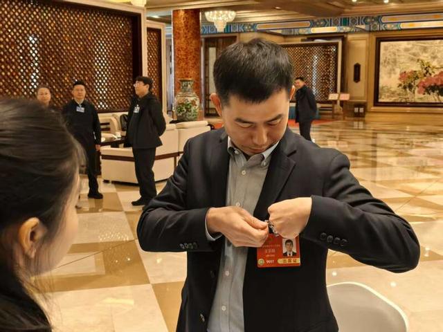 3月3日，北京会议中心驻地，出席十四届全国人大三次会议的北京团代表陆佩戴代表证。中青报·中青网记者 尹希宁/摄