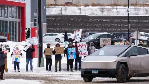 图注：美国特斯拉某展厅外，人们举着抵制马斯克的标语