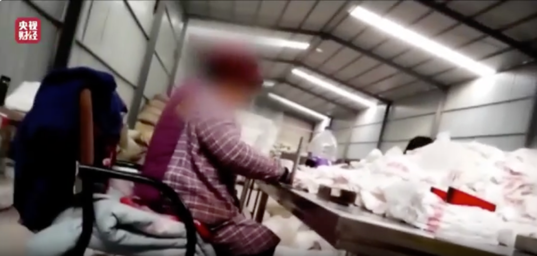 一次性内裤生产作坊内，工人直接用手触碰内裤。图 / 央视频截图