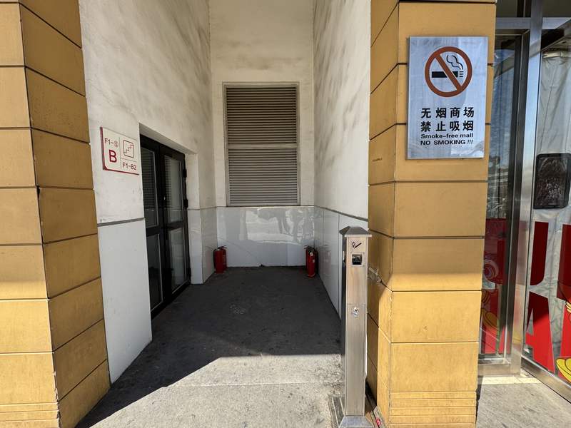 首开·福茂购物中心南门外的吸烟区，墙上挂着“无烟商场 禁止吸烟”的牌子。新京报记者 王景曦 摄