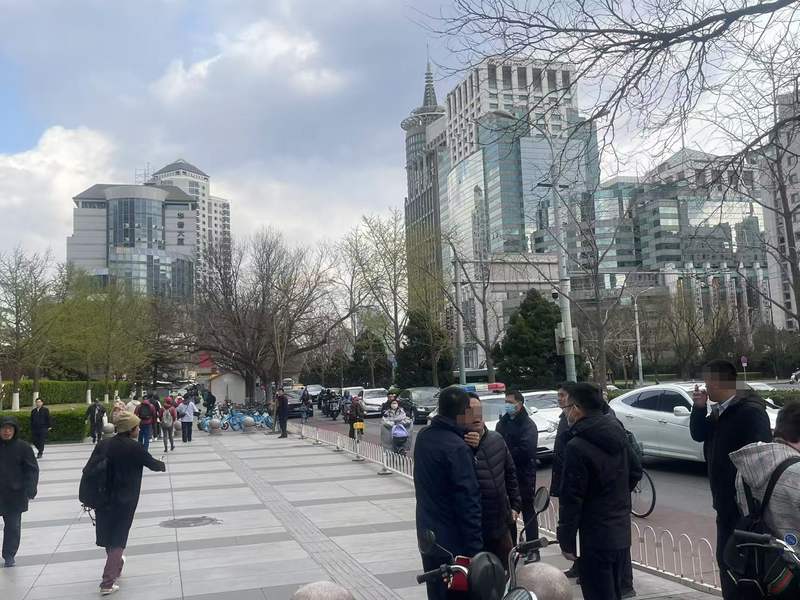 3月28日下午，2号线朝阳门地铁口，几位男士聚在一起聊天，其中有两位手中有点燃的香烟。新京报记者 吴婷婷 摄