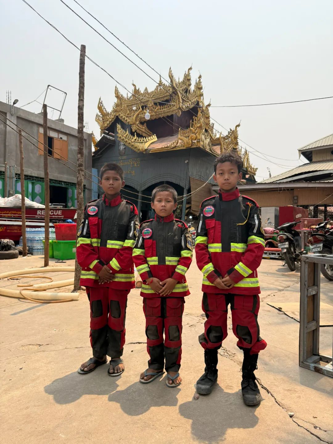 ▲三位少年义务消防员，他们身后佛教风格的建筑是消防站。新京报记者 丛之翔 摄