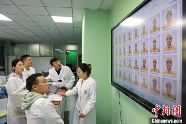 4月2日，在四川大学法医教学楼内，梁伟波教授(右二)与学生一同观看部分复原的烈士容貌图片。记者 王磊 摄