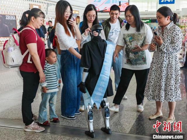 图为人形机器人吸引旅客参观。中新社记者 张畅 摄