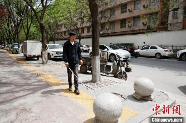 图为谭维乐借助盲杖独立出行。 梅镱泷 摄