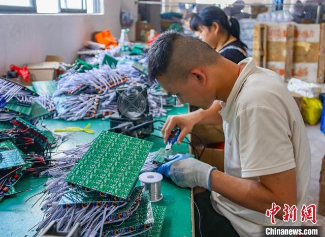 图为工人组装、检测电子产品。周火文 摄