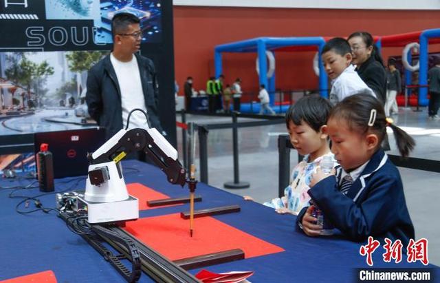 5月24日，青海西宁，小朋友观看绘画写字机器人创作。中新社记者 马铭言 摄