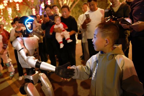 5月6日晚，甘肃省兰州黄河风情线大景区，小朋友与机器人“小兰”互动握手。视觉中国供图