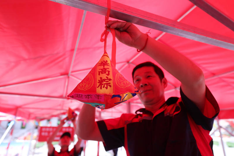 遮阳篷下挂着写有“一举高粽”等祝福语的粽子。新京报记者 李木易 摄