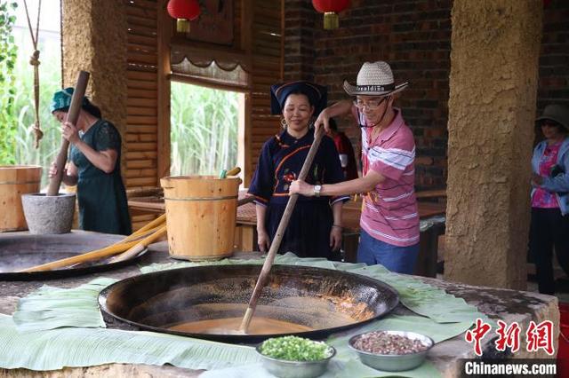 图为游客在崇左市江州区卜花村体验古法手工红糖制作。江州区融媒体中心供图