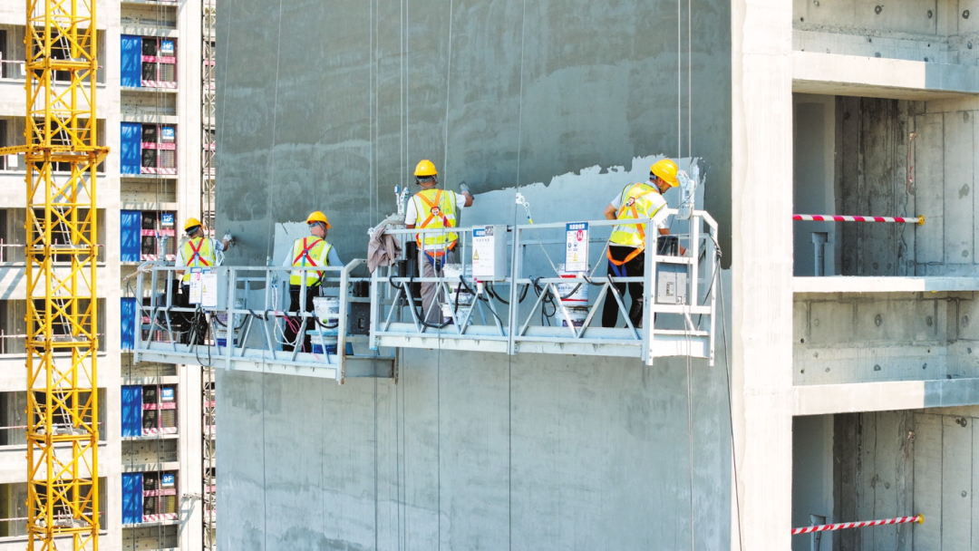 现场,工人在吊篮内进行楼体外墙刮