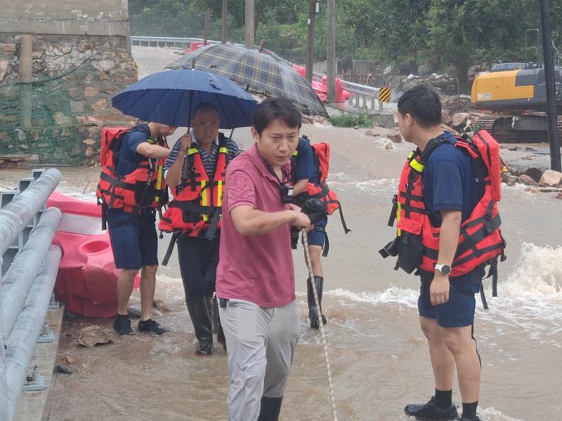 暴雨期间，王海山（左前）和救援人员拉线转移群众。平谷区委宣传部供图
