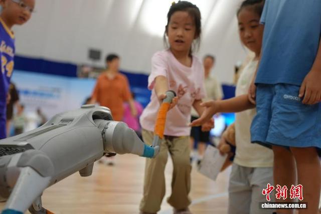 图为儿童与机器狗握手。 吴敏 摄