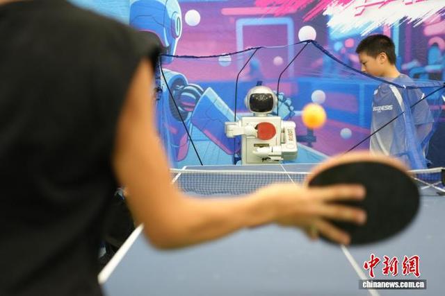 图为乒乓球机器人和青少年练球。 吴敏 摄
