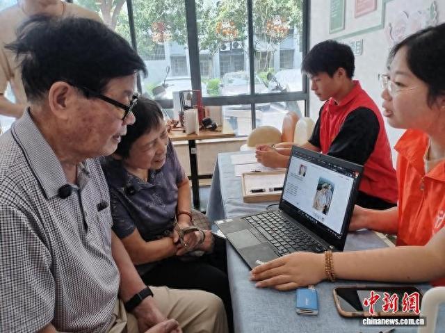 一对老夫妻挑选通过AI处理背景的照片。杭州上城区凯旋街道 供图