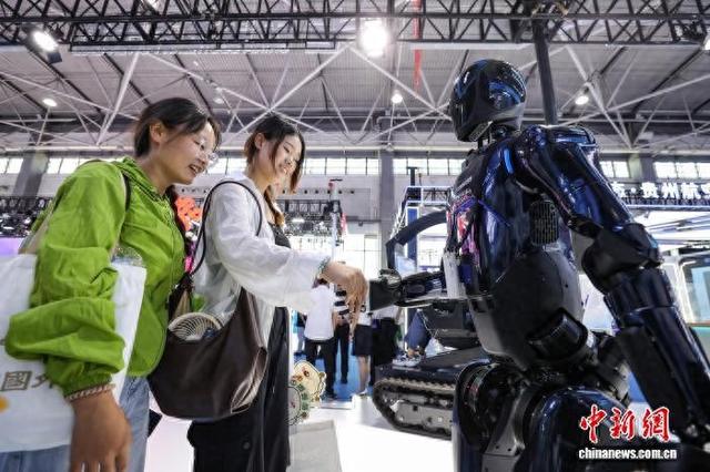 8月28日，在2025数博会展馆，参观者在中国南方电网展区和“大瓦特”人形机器人握手互动。中新社记者 瞿宏伦 摄