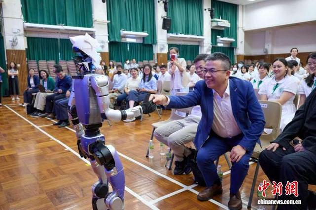 图为培侨中学校长伍焕杰与机器人现场互动。(主办方供图)