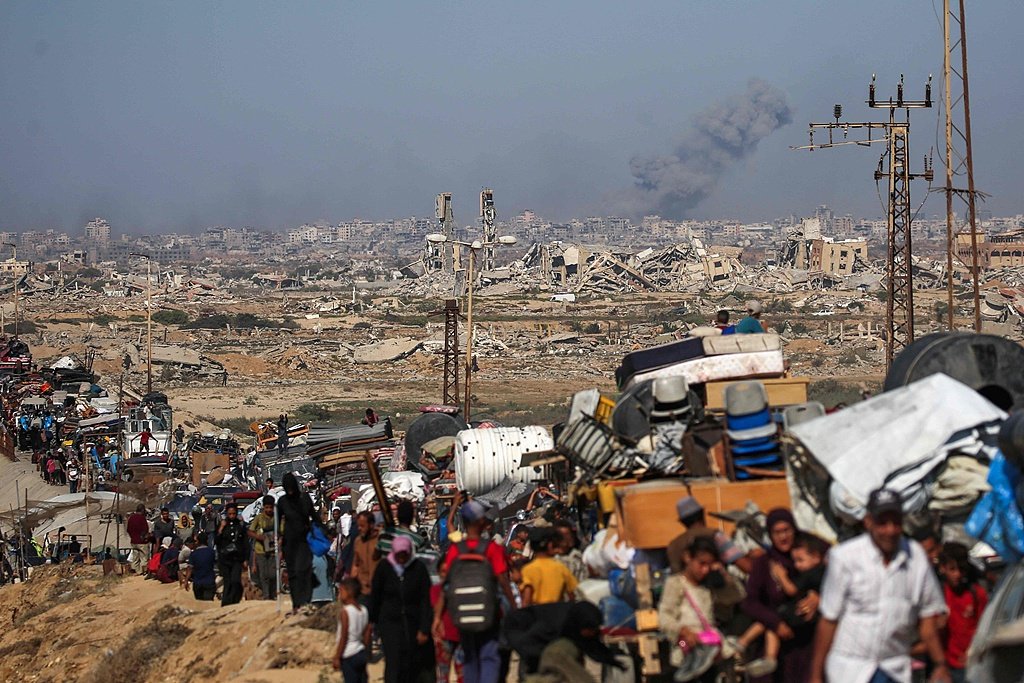 9月14日，加沙地帶中部努賽賴(lài)特難民營(yíng)，以色列襲擊加沙城時(shí)濃煙滾滾，流離失所的巴勒斯坦人帶著(zhù)他們的財物向南遷移。