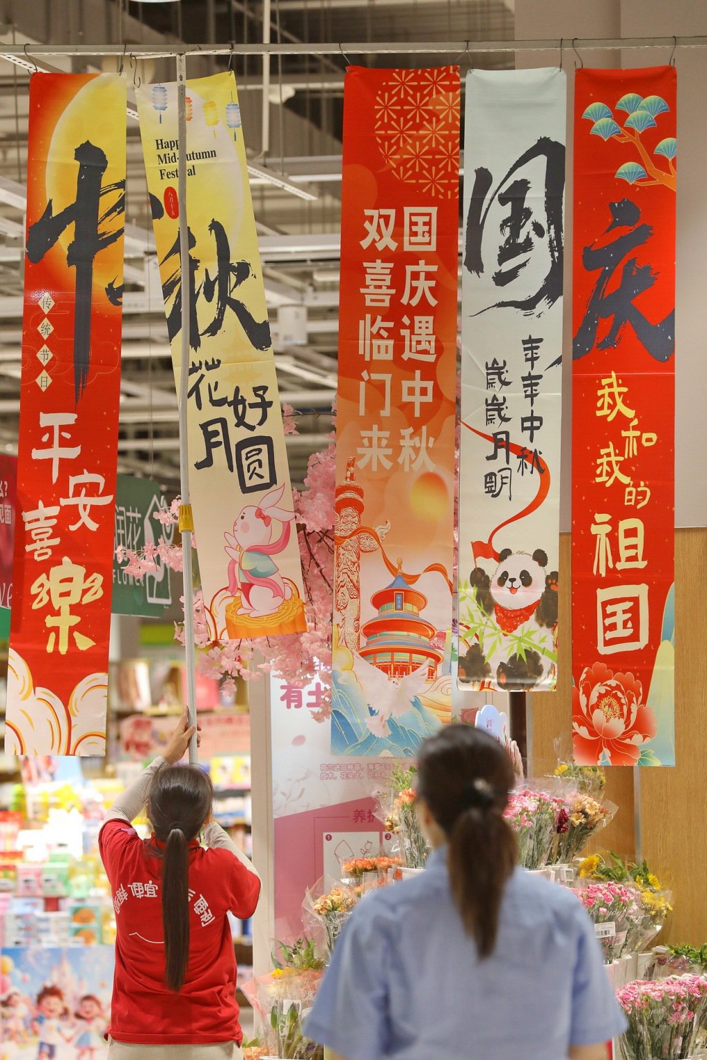 9月24日,浙江嘉兴,一家大型商场工作人员悬挂国庆中秋宣传条幅