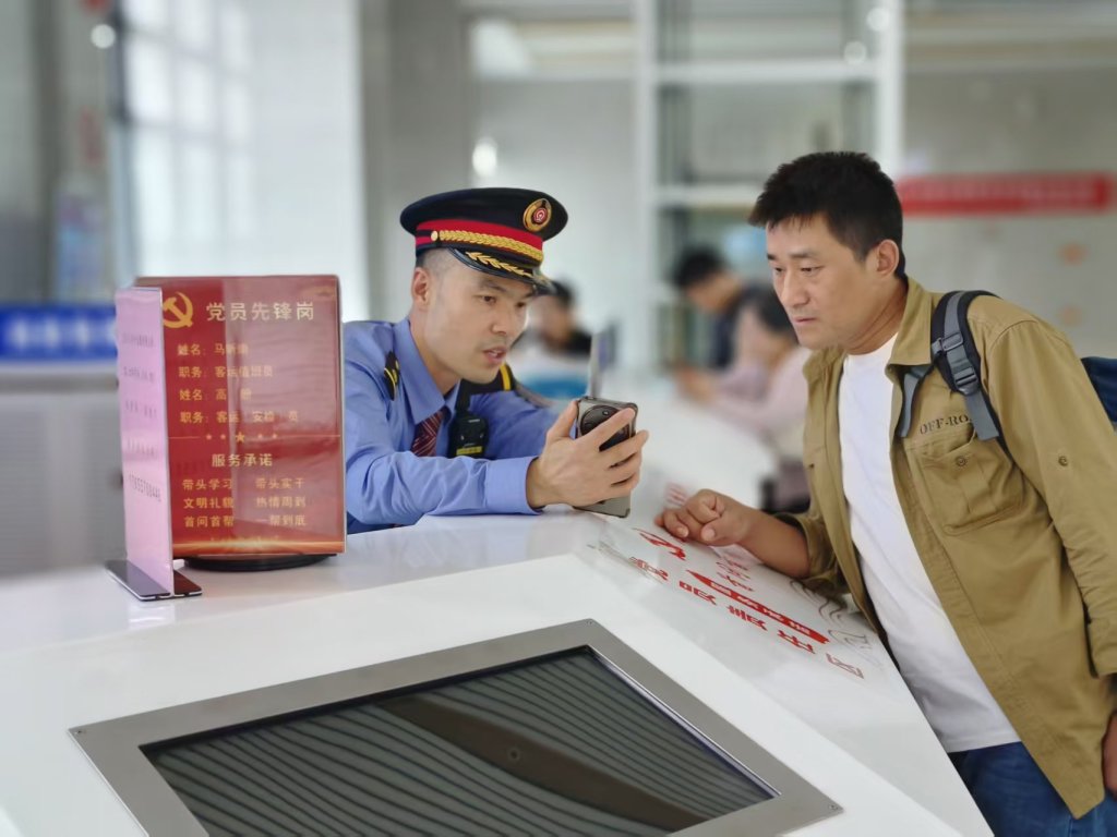 雷锋服务台党员指导旅客通过手机12306办理电子临时身份证乘车。