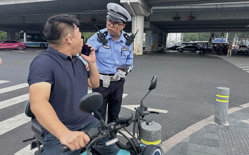 交警拦停了一位边骑电动自行车边打电话的市民。新京报记者 王贵彬 摄