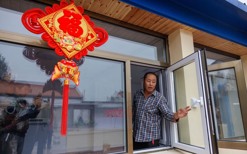 10月15日，密云区高岭镇瑶亭村，村民王以庄正在查看新装的窗户，他特意挂上了喜庆的中国结。新京报记者 王子诚 摄