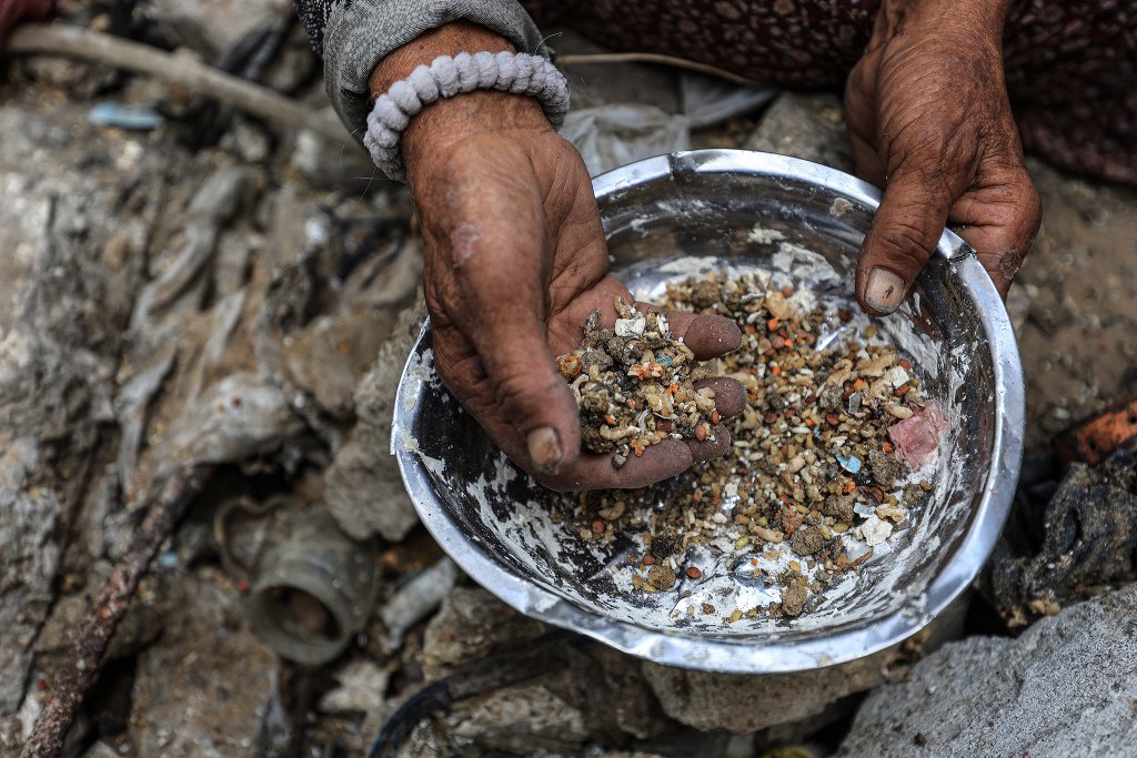 當(dāng)?shù)貢r(shí)間2025年7月30日，加沙地帶加沙城，亞爾穆克難民營(yíng)，人們正在從垃圾中撿拾食物殘?jiān)?。視覺中國(guó) 圖