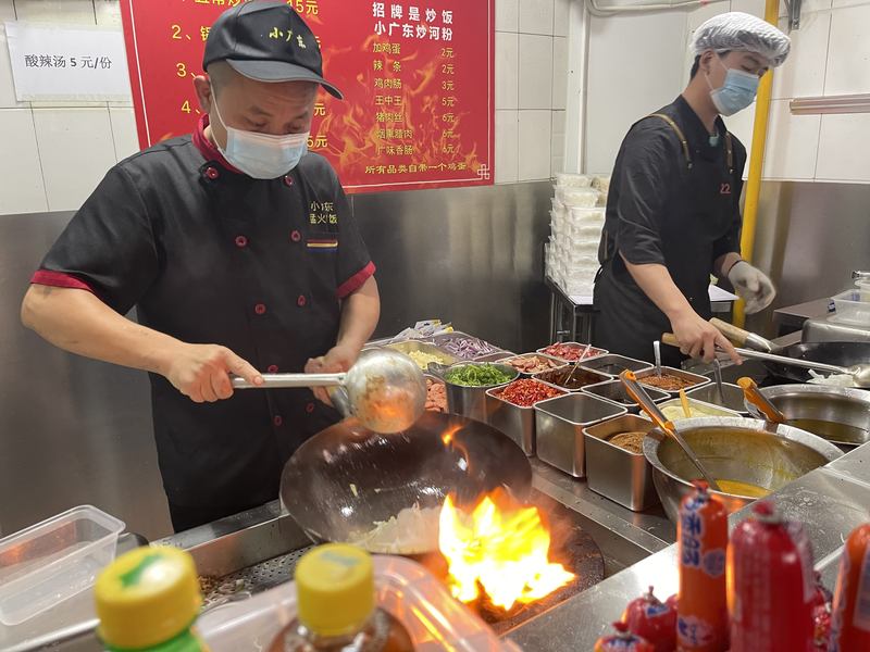 新的档口干净整洁，王鑫林（左）开足火力猛火现炒。新京报记者 吴婷婷 摄