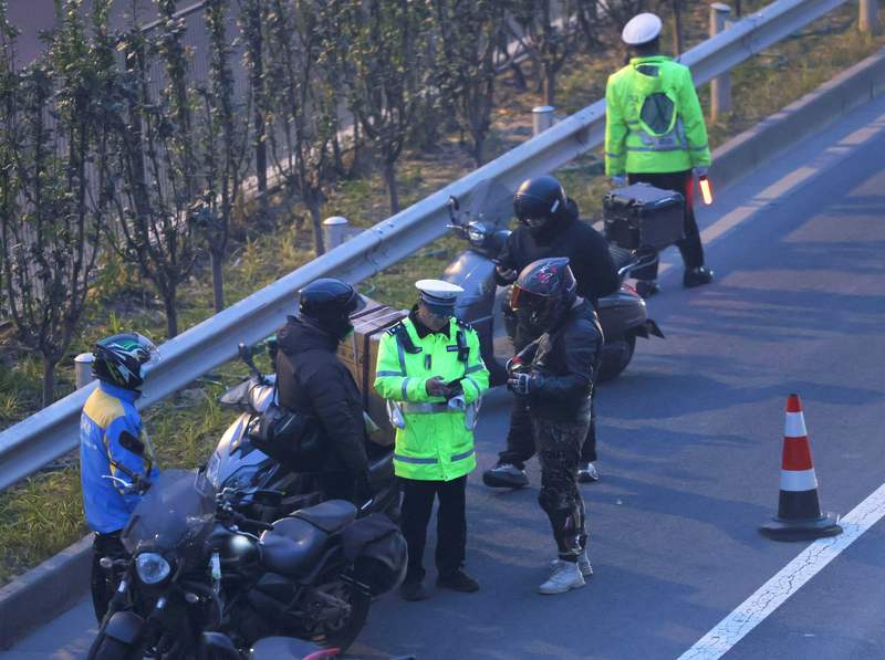 交警对违法占用应急车道的摩托车骑行者现场开具罚单。新京报记者 王贵彬 摄
