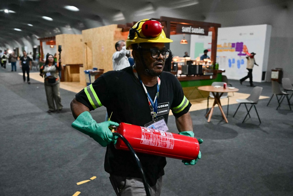 11月20日，一名工作人員肩扛滅火器奔跑。