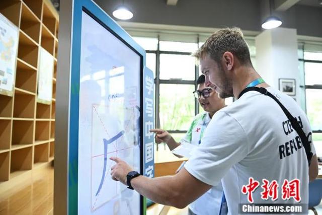 2023年7月27日，在成都第31届世界大学生夏季运动会运动员村，外籍运动员在志愿者的引导下学写汉字。中新社记者 陈超 摄