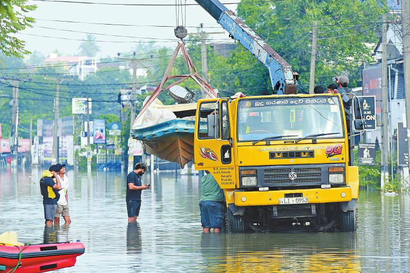 12月1日，在斯里兰卡首都科伦坡郊区，工作人员用吊车运送救援船只。 新华社发（加扬·萨米拉 摄）