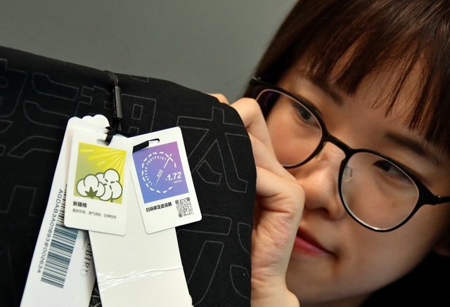 产品碳足迹指产品全生命周期各环节所产生的碳排放量总和。图为一家服装企业员工展示碳标识。摄影/章轲